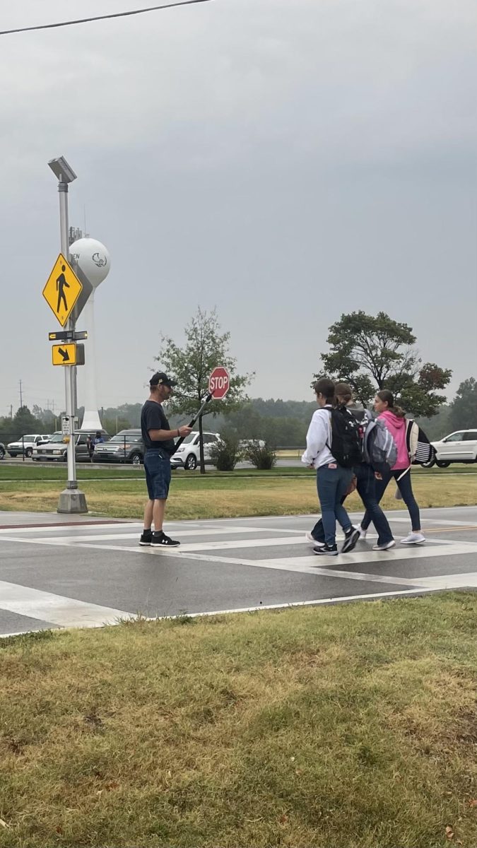 Kenny greets students at the crosswalk on a rainy day. 
